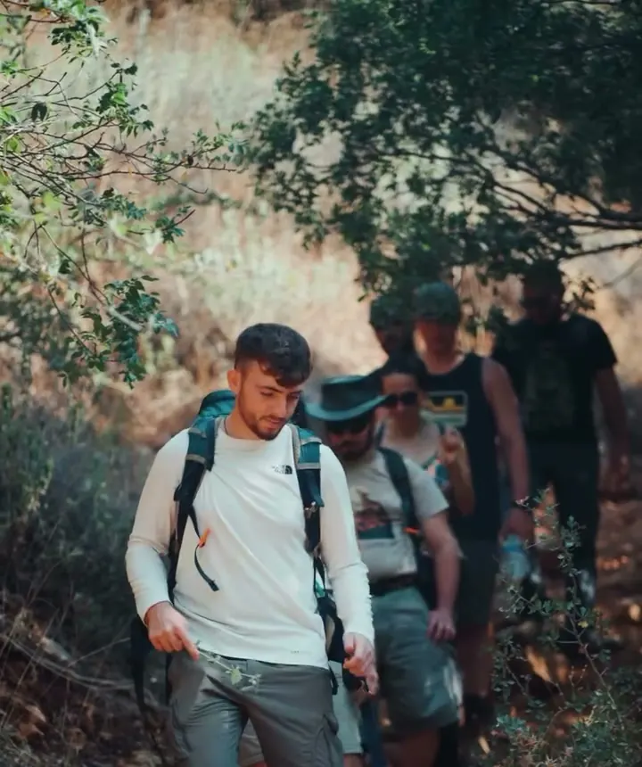 גיא מוביל קבוצה בשביל בין עצים, עם תרמילים על הגב
